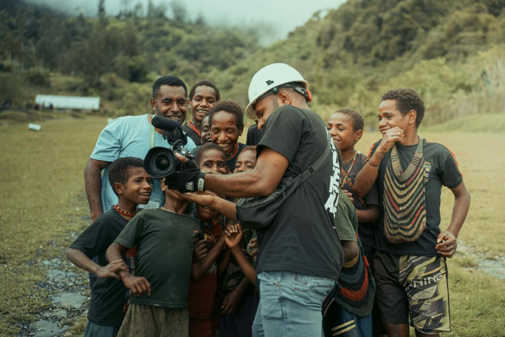 Group of people enthusiastically engaging with camera outdoors in lush, green setting.