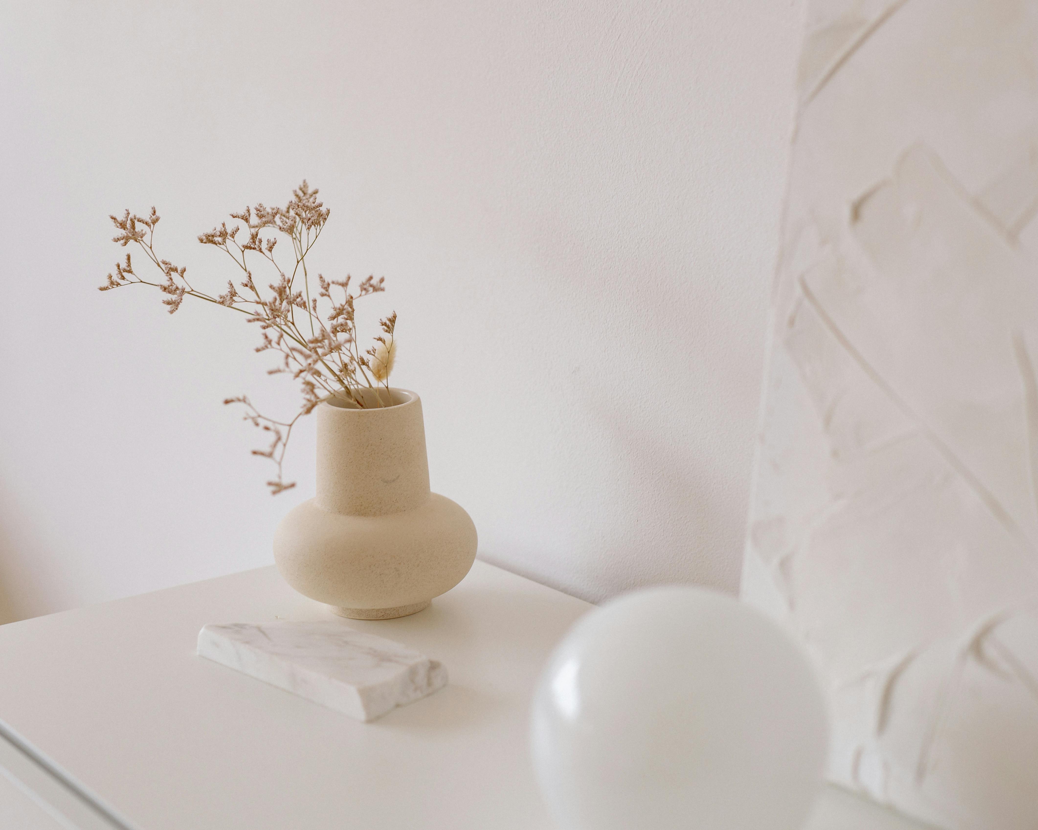 Elegant ceramic vase with dried flowers on a minimalist table setting, perfect for modern interiors.