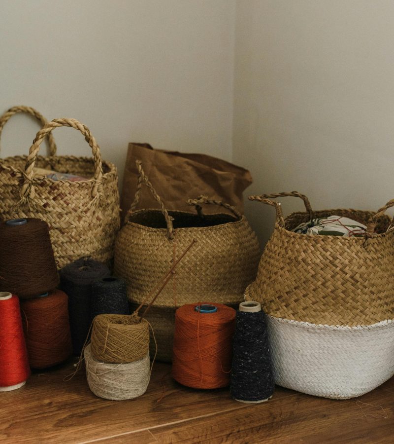 Warm craft space featuring yarn rolls and handmade woven baskets on a wooden floor.