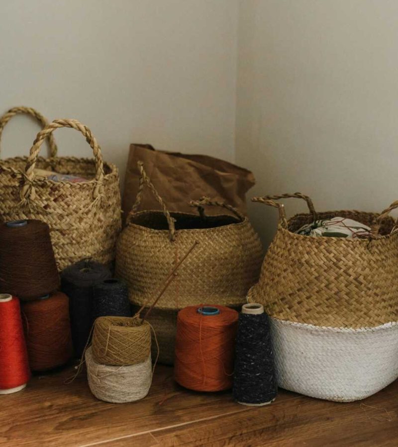 Warm craft space featuring yarn rolls and handmade woven baskets on a wooden floor.