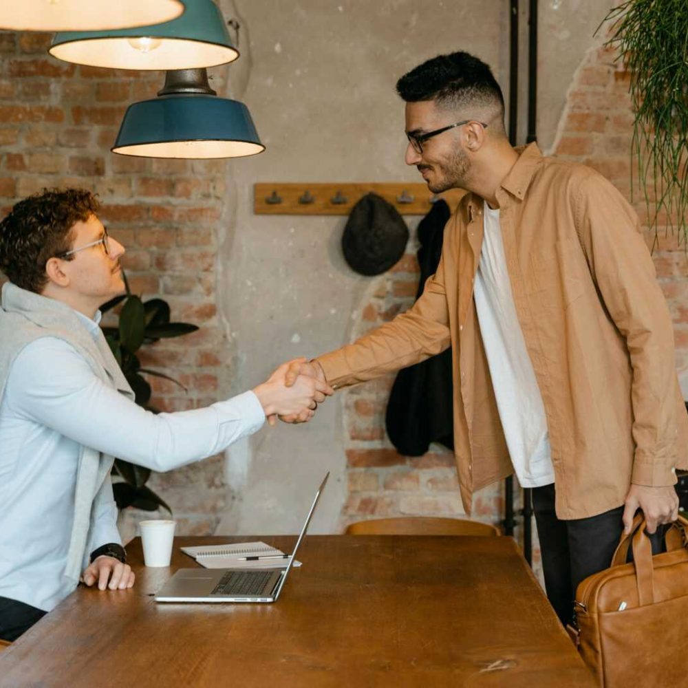 Two businessmen shake hands in a modern office setting, sealing a partnership.